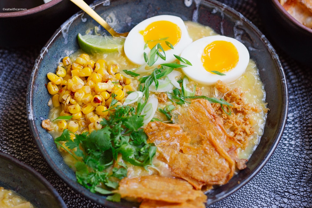 with all the toppings, soft boiled egg, crispy chicken skin, fried garlic, corn, cilantro, lime, green onions
