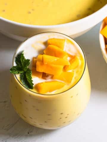 Cool, creamy mango sago in a glass topped with fresh mango cubes and mint