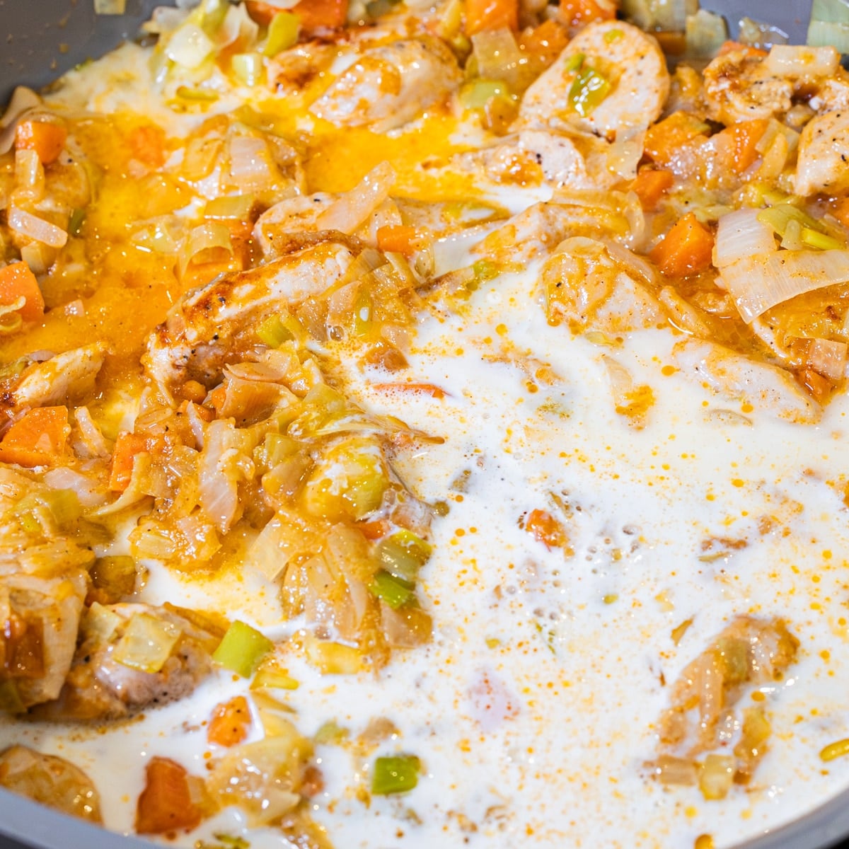 white wine, chicken bouillon, water, and cream being added to skillet chicken pot pie base
