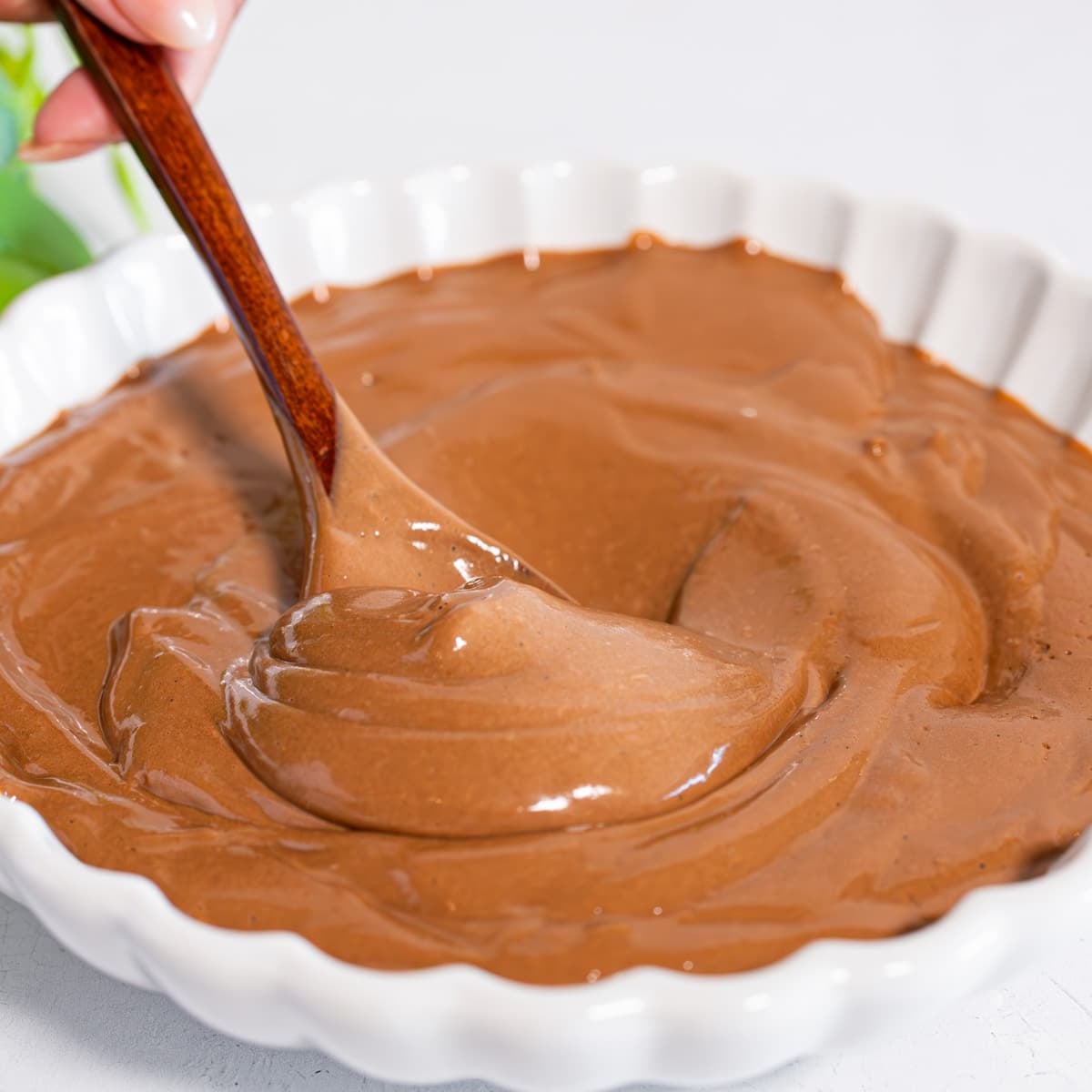 boiled egg chocolate pudding with cocoa powder and honey in bowl being stirred to show consistency