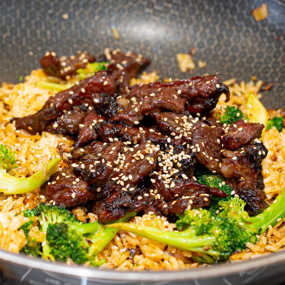 Beef and broccoli fried rice with velveted beef strips sesame seeds and green onions served straight from the wok
