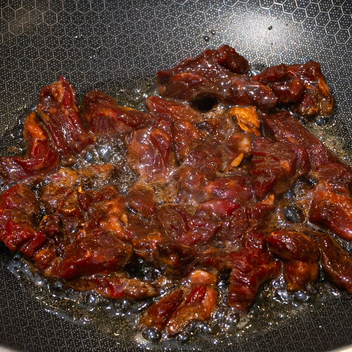 Velveted beef strips searing in a screaming hot HexClad wok until deeply caramelised