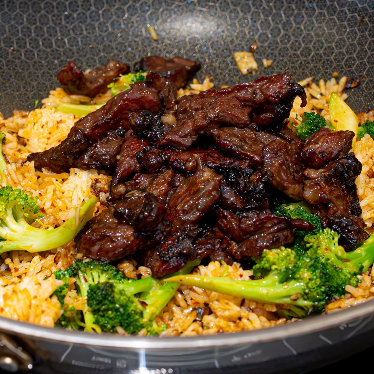 Beef strips broccoli and day old rice tossed together in a wok with dark soy chili crunch and sesame oil