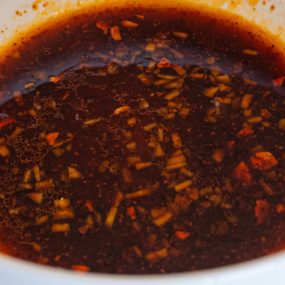 Honey soy dressing with chili crunch and ginger whisked together in a bowl