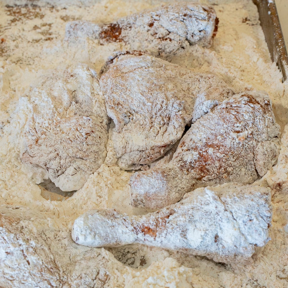 Chicken pieces dredged and pressed into the seasoned flour coating