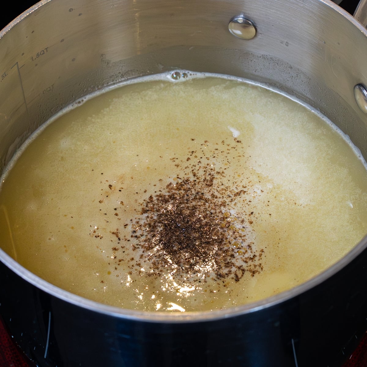 Brown gravy simmering with soy sauce, bouillon, and black pepper in a pot