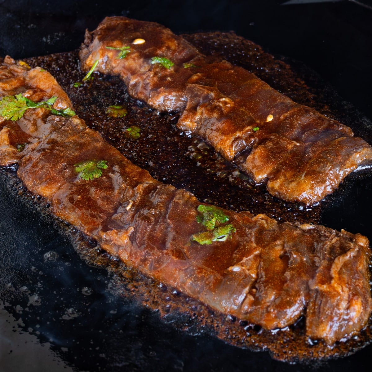 Asian marinated skirt steak grilling on high heat with caramelized honey sriracha glaze