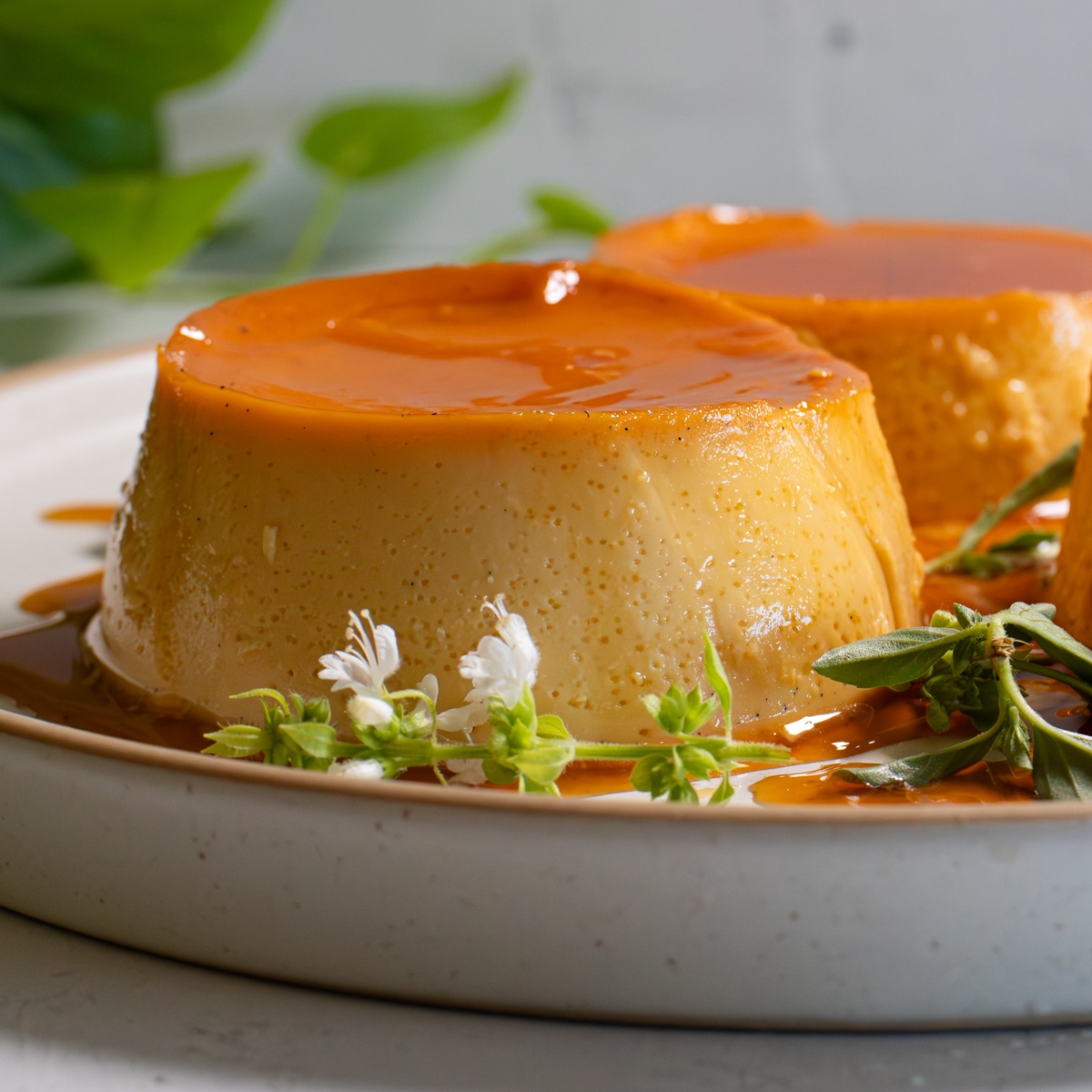 Classic Filipino leche flan on a plate with golden caramel and fresh herbs