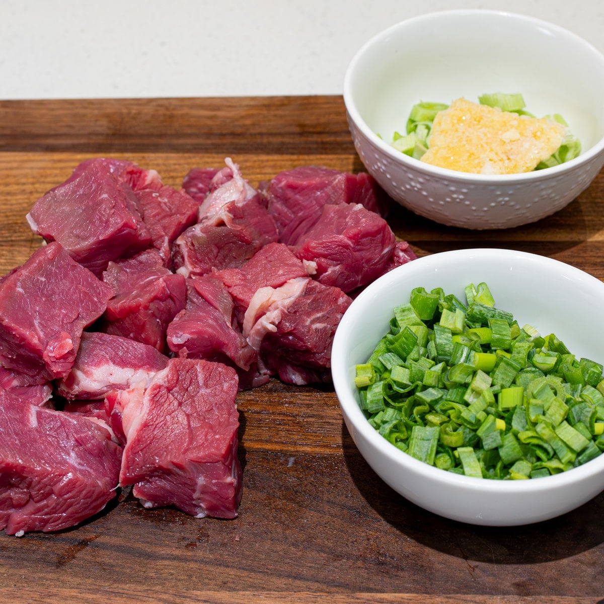 Cubed ribeye with bowls of minced garlic and chopped green onion