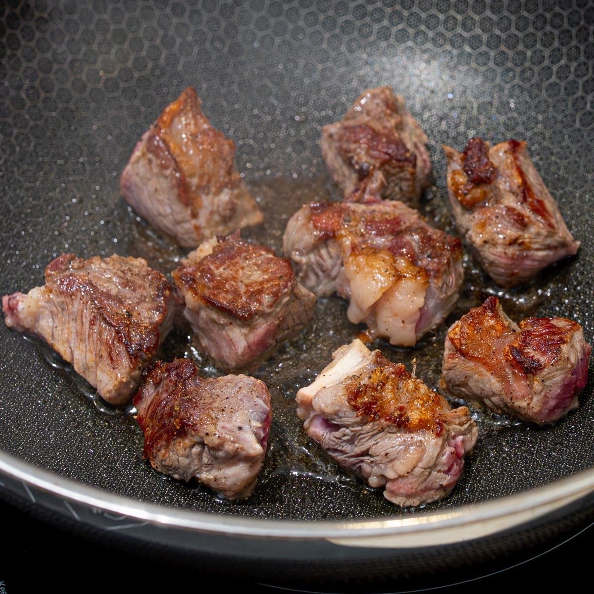 Ribeye steak cubes searing in a hot wok